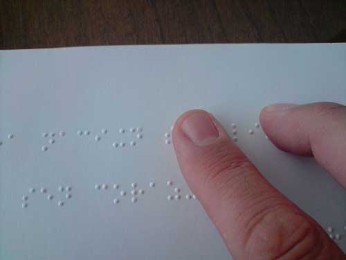 a finger reading a page of Braille