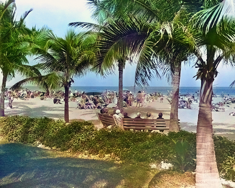 Highly saturated colorized photograph of a beach filled with people and palm trees