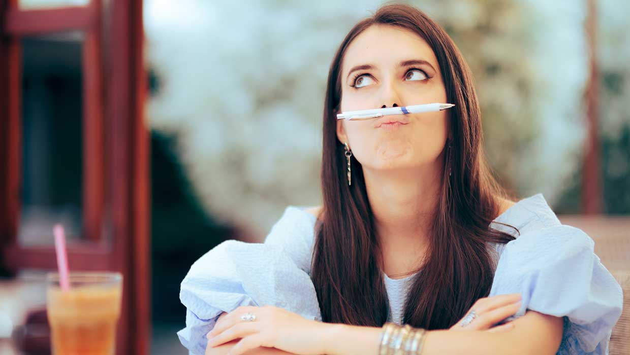 woman with pen balanced on her top lip using her imagination to generate creative ideas