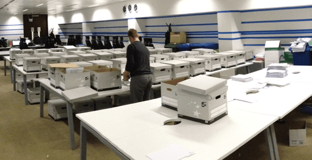Russell Viers working in a room full of tables covered in bankers boxes