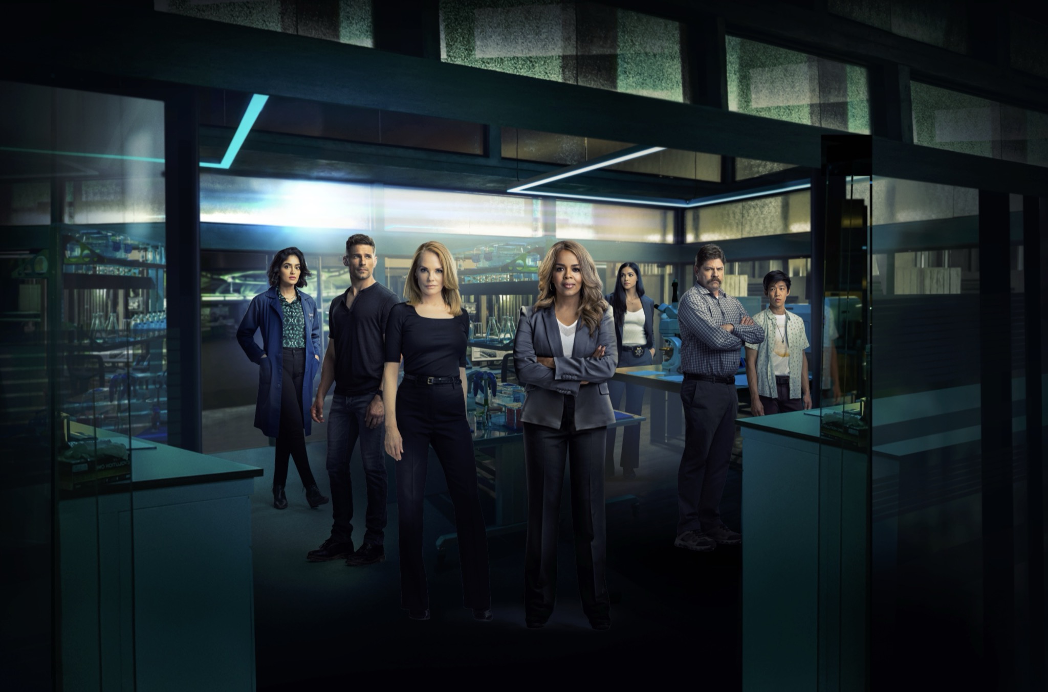 A composited image of the main cast from the TV series NCIS. A group of people are standing in a dark forensics lab with lots of angles and glass.
