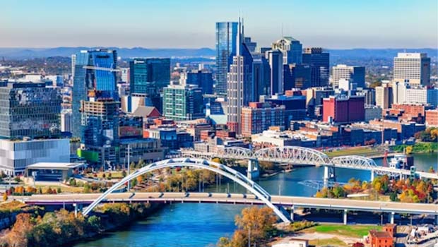 City skyline with a white arched bridge over a blue river, downtown buildings in the background.